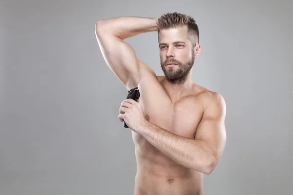 Bello uomo barbuto con un trimmer rasatura fuori i capelli del corpo — Foto Stock