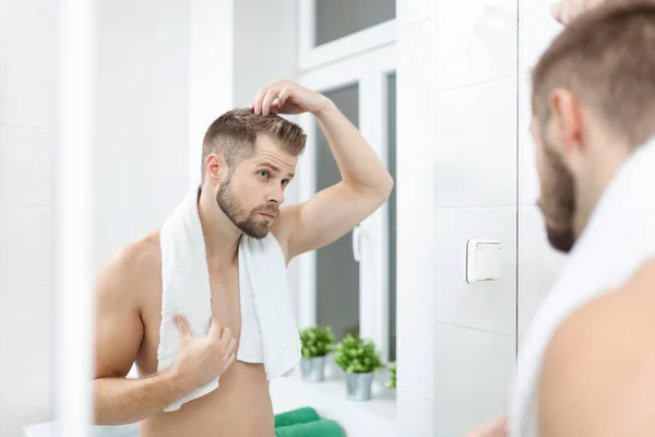 Komea nuori mies huolissaan hiustenlähtö — kuvapankkivalokuva