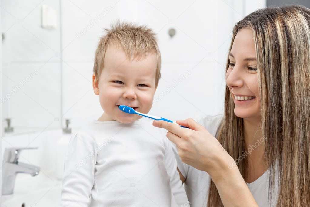 Happy mother teaching her son how to bush teeth