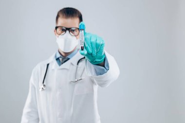 Coronavirus Covid-19 kan testi örneğini tutan solunum maskesi takan bir sağlık görevlisi., 