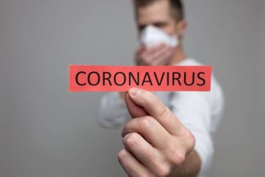 Coronavirus Covid-19 işareti taşıyan solunum maskesi takan endişeli bir adam.