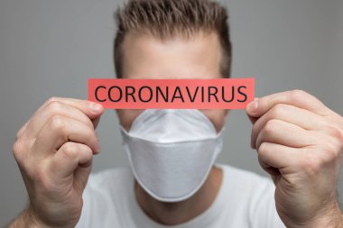 Coronavirus Covid-19 işareti taşıyan solunum maskesi takan endişeli bir adam.