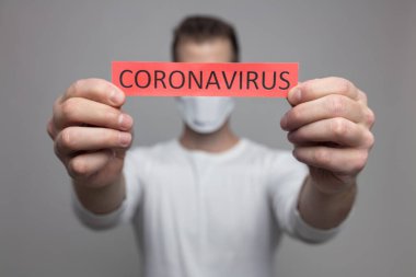 Coronavirus Covid-19 işareti taşıyan solunum maskesi takan endişeli bir adam.