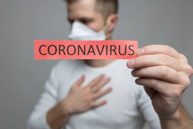 Coronavirus Covid-19 işareti taşıyan solunum maskesi takan endişeli bir adam.