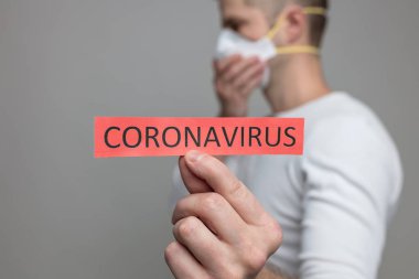 Coronavirus Covid-19 işareti taşıyan solunum maskesi takan endişeli bir adam.