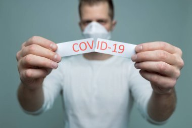 Coronavirus Covid-19 işareti taşıyan solunum maskesi takan endişeli bir adam.