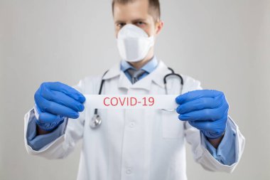 Doktor solunum maskesi takıyor ve Coronavirus Covid-19 kan örneğini tutuyor. 