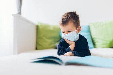 Coronavirus Covid-19 'a karşı önlem olarak solunum maskesi takan mutsuz bir çocuk.