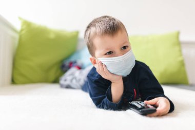 Coronavirus Covid-19 'a karşı önlem olarak solunum maskesi takan mutsuz bir çocuk.