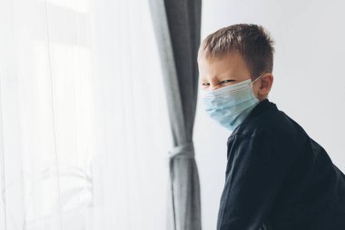 Coronavirus Covid-19 'a karşı önlem olarak solunum maskesi takan mutsuz bir çocuk.