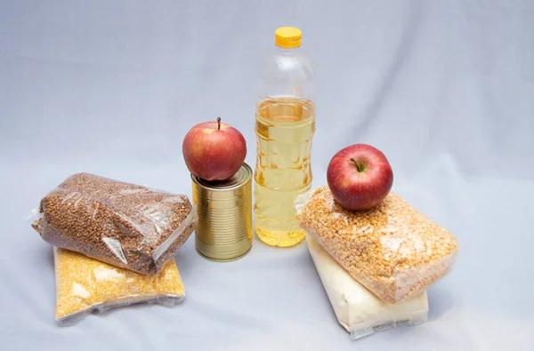 Un conjunto de productos comestibles. Cereales, manzanas, aceite vegetal. Caridad. Fondo azul claro. Naturaleza muerta de los productos alimenticios . — Foto de Stock