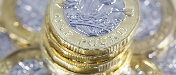 British Currency - Stack of British One Pound Coins with selective focus in a panoramic format