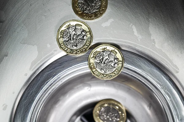 Wasting Money Concept - money down the drain in a horizontal format with selective focus