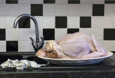 Raw poultry defrosting in a domestic kitchen with a dish cloth near by creating a cross contamination senario clipart