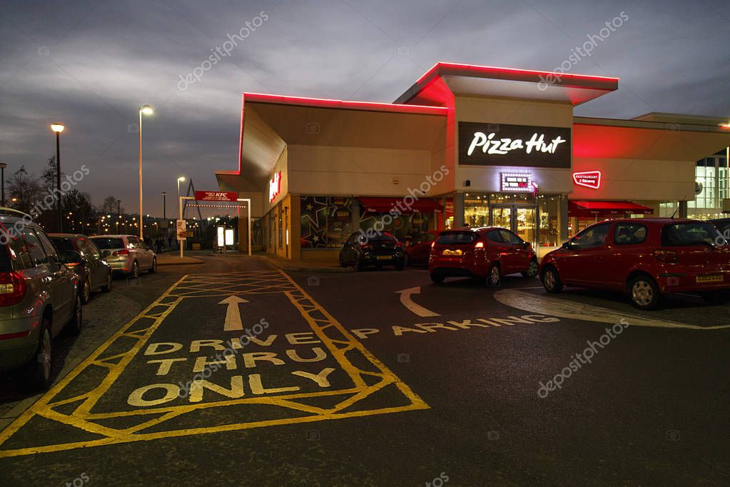 Swansea, UK: December 27, 2016: People walk past a night time drive through. Pizza Hut is an American restaurant and franchise known for its Italian-American cuisine menu including pizza and pasta.