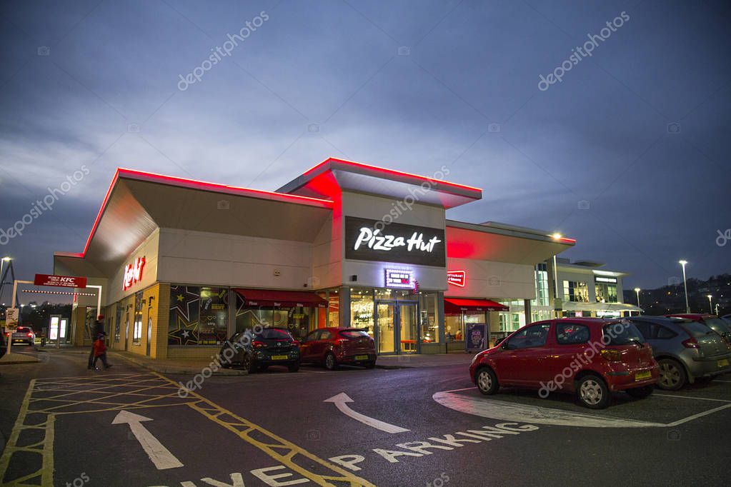 Swansea, UK: December 27, 2016: People walk past a night time drive through. Pizza Hut is an American restaurant and franchise known for its Italian-American cuisine menu including pizza and pasta.