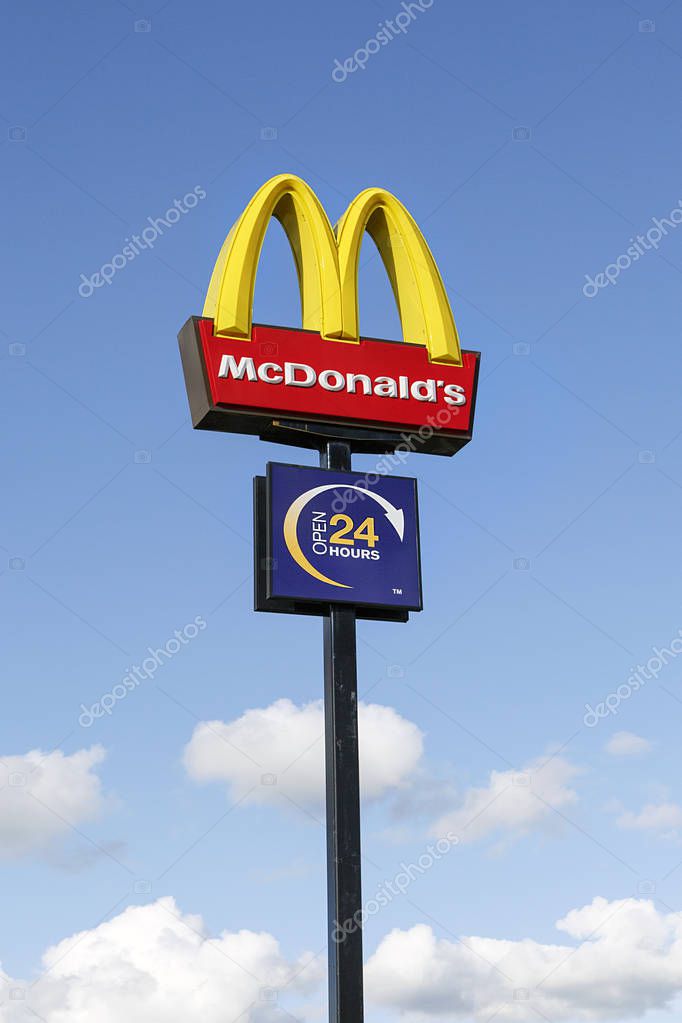 Swansea, UK: September 21, 2017: McDonald's logo on a pole against a blue sky. McDonald's is the world's largest chain of hamburger fast food restaurants and this one is open 24-7