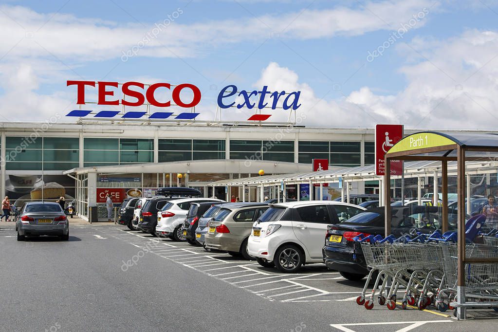 Swansea, UK: July 09, 2017: Front view of a Tesco Extra Superstore in Wales. Tesco PLC is a British multinational grocery and general merchandise. Shoppers are entering or leaving the shop.