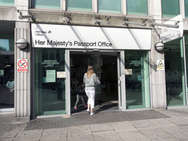 London, UK: July 27, 2016: A woman enters Her Majesty's Passport Office.The Official Passport Office in London offers Premium One Day Appointments and Fast-Track One Week Appointment Services.