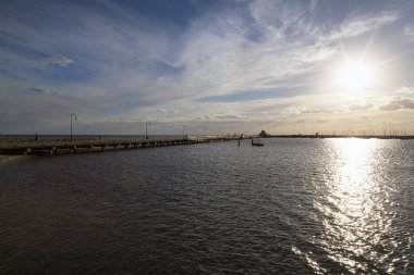 Güneş ikonik küçük Mavi Köşk iskelede St Kilda batıyor. Yat Gemi direkleri ışıkta kontrast.