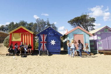Brighton Beach, Avustralya: 31 Mart 2017: bir grup arkadaşıyla sakin ol Brighton Plajı Melbourne renkli ve ikonik plaj kulübe tarafından. 