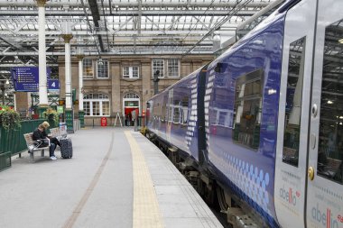 Edinburgh Uk: 26 Mayıs 2016: Scotrail tren bekleyen Waverley tren istasyonu Scotrail İskoçya'da tren Scotrail markası altında işletilen İskoç demiryolu şirketlerin bir dizi ifade eder. İki kişi bir tren için bekleyin.