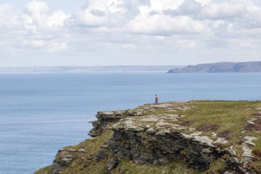 Cornwall, İngiltere: 14 Nisan 2016: bir turist Tintagel, bir uçurumun en iyi yürüyüş sahiptir. Tintagel popüler bir tatil beldesi olan dramatik cliff üstleri ve kıyı sahne nedeniyle olduğunu.