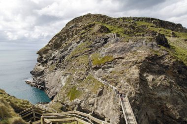 Cornwall, İngiltere: 14 Nisan 2016: Tintagel adaya ahşap köprüyü geçtikten turistler. Tintagel ayrıca İngiltere diğer siteler için sorumlu İngiliz Heritage tarafından yapılmaktadır.