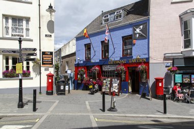 Tenby, İngiltere: 05 Temmuz 2016: Cankurtaran Tavern bir popüler balıkçı köyü Tenby geleneksel Galce barda olduğunu. Bir kadın sokak bir kafede oturuyor.