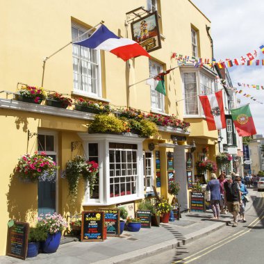 Tenby, İngiltere: 05 Temmuz 2016: turist yürümek korsan Inn Tenby geçmiş. Yaz aylarında açık renklerle boyalı pub Tenby ziyaretçileri ile çok popüler tatil sezonu bir kare biçiminde