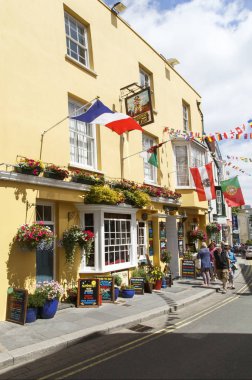 Tenby, İngiltere: 05 Temmuz 2016: turist yürümek korsan Inn Tenby geçmiş. Yaz aylarında açık renklerle boyalı pub Tenby ziyaretçileri ile çok popüler tatil sezonu bir dikey biçimde