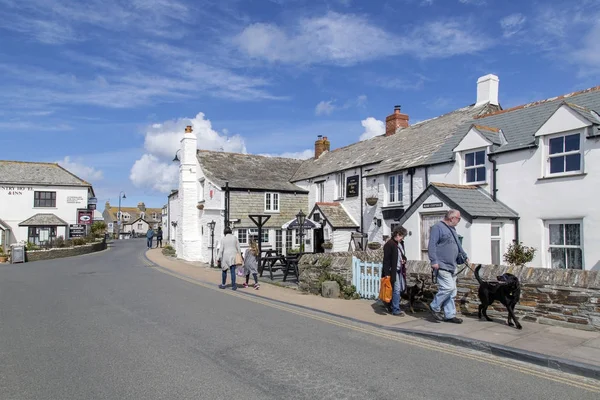 Tintagel, Cornwall, İngiltere: 14 Nisan 2016: Cornwall Tintagel popüler turistik köy sokak görünümü. Bir çift onların köpekleri yürüme ve anne ve kızı kameradan uzak yürüyor.