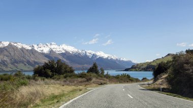Gölü kıyısındaki Wakatipu bir yolda yolculuk Queenstown ve Glenorchy - South Island Yeni Zelanda arasında. Dikkat çekici dağ silsilesi hala var doruklarına kış, kar.