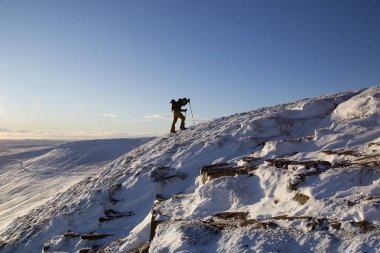 Pen y Fan, Galler, Birleşik Krallık: 11 Aralık 2017: Pen y Fan dağ Brecon Beacons National Park içinde mavi gökyüzü ve kış kar koşulları ile zirvesine tırmanmak için kayaklar bir adam kullanır
