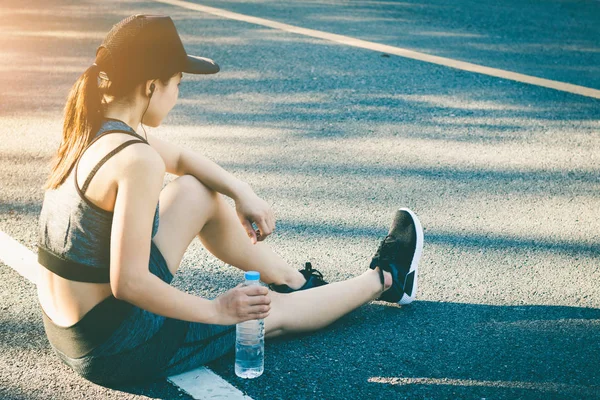 Las mujeres jóvenes dejan de beber agua descansando después de correr . — Foto de Stock