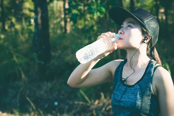 Las mujeres jóvenes dejan de beber agua descansando después de correr . — Foto de Stock