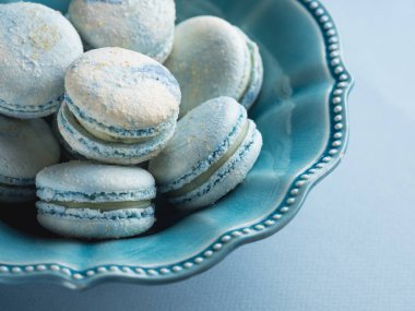 close-up of blue french macarons in ceramic plate on table clipart