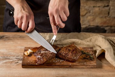 Erkek el Close-Up ızgara et baharatlar ile ahşap tahta üzerinde kesmek. 