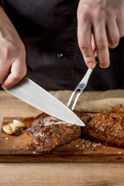 Erkek el Close-Up ızgara et baharatlar ile ahşap tahta üzerinde kesmek. 