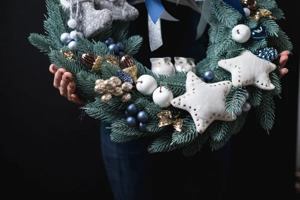 close-up of female holding beautiful Christmas wreath on black background