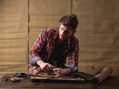 ahşap masa üzerinde deri ile kırmızı gömlekli sakallı yakışıklı