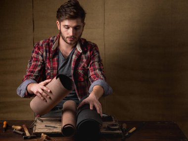 ahşap masa üzerinde deri ile kırmızı gömlekli sakallı yakışıklı