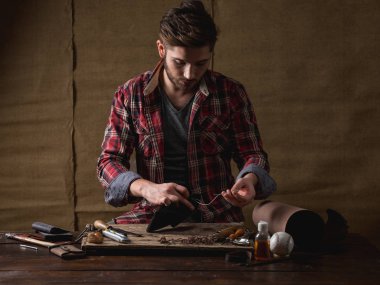 kırmızı gömlekli sakallı yakışıklı deri cüzdan ahşap masa üzerinde dikmek