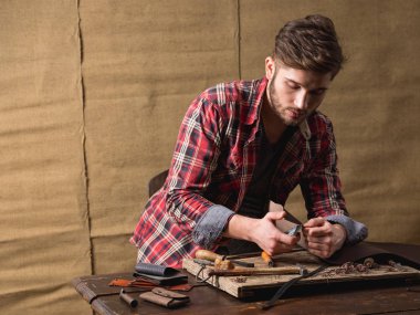 ahşap masa üzerinde deri ile kırmızı gömlekli sakallı yakışıklı