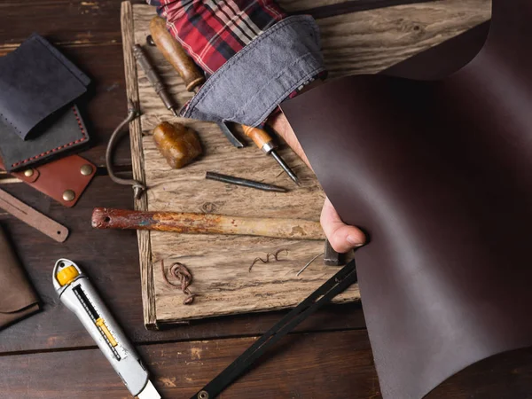 close-up of male hands with leather on wooden table