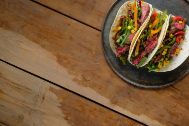 Ahşap arka plan üzerinde siyah plaka üzerinde lezzetli tacos