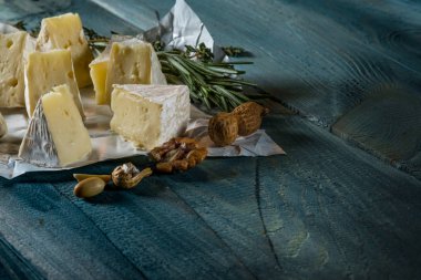 rustik düz lay camamber peynir dilimleri, otlar ve mavi ahşap arka plan, kopya alanı ile üstten görünüm fındık ile