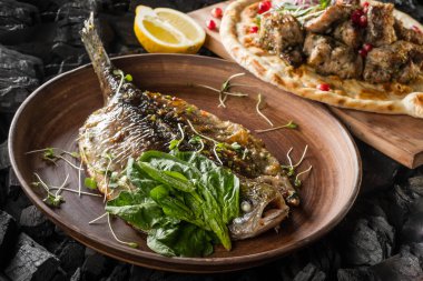 Balık ve otlar ve et ve kömür pişirme baharatlar ile ev yapımı ekmek ile plaka