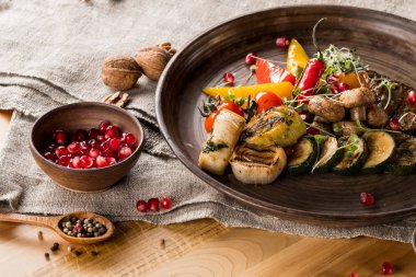 Nar ile kase tahıllar, ahşap masa üzerinde baharatlar ile plaka, ceviz ve tahta kaşık ızgara sebze, yakın çekim