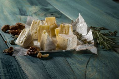 rustik düz lay camamber peynir dilimleri, otlar ve mavi ahşap arka plan, kopya alanı ile üstten görünüm fındık ile